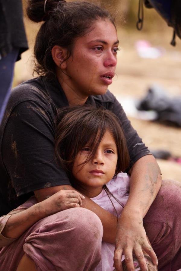 A woman and child covered in mud after wading into the US when officials cut wired fences along the border. 