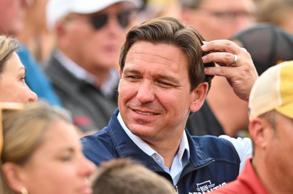 Ron DeSantis scratches his head in a crowd of people.